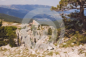 At the top of mount AI-Petri, the cable car building, pine and a scattering of stones in the foreground