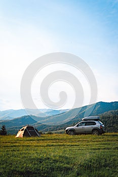 On the top of the mountain A tourist tent and a four-wheel driveSUV vehicle with a roof rack. concept of freedom and travel by car