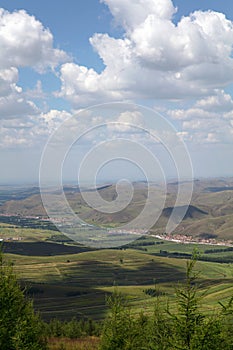 The top of the mountain in Zhangbei County looks at the grassland scenery under the blue sky and white clouds