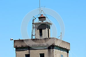 Top of old dilapidated fire station tower with large vintage retro siren and metal ladder mounted on one side