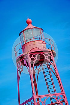 The top of an old lighthouse against a blue sky.