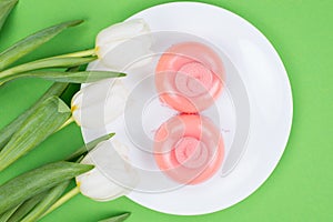 Top overhead above close up view photo of two nice cakes on plate with three lovely tulips isolated green background
