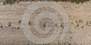 Top panorama view from above on surface of gravel road with car tire tracks