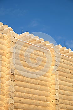 Top part of big rural house wall constructed from sandy brown smooth planed heavy pine logs