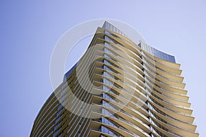 Top part of a modern corporate building with yellowish overhangs in each floor.