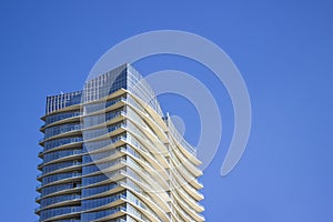 Top part of a modern and stylish corporate building with yellowish overhangs in each floor.