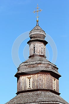 Top part of traditional wooden ukrainian church with a golden cross, cossack period