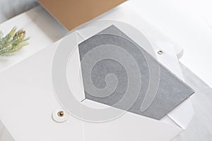 Top perspective view of blank grey card in white envelop with pine leaf on two layer step of marble table top.Mock up template for