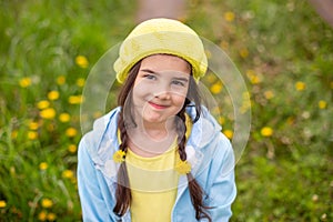 Top Portrait of a charming little girl with two pigtails with woven dandelions