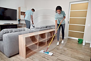 Top quality janitorial team. Two professional cleaners working together in the living room. Young afro american woman