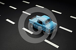 Top and rear view of a blue colored fifties toy model car on an asphalt road with road lanes