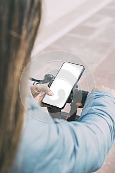 top rear view of latina woman riding electric scooter using smart phone white screen, for apps