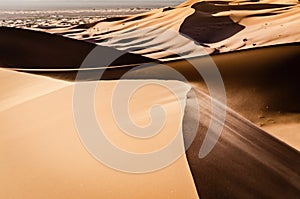 Top of a sand dune with sand being blown over by the wind. Desert landscape. Erg Chebbi, Morocco