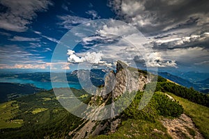 Top of Schafberg mountain and view on Attersee on a sunny day with dramatic cloudy blue sky