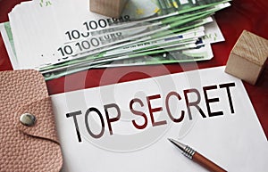 Top secret words on copybook, pen, money and leather wallet. Business concept