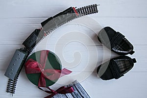 Top set of gifts on white wooden background. Presents, toys, baby shoes, toy train, berries organized with space for text