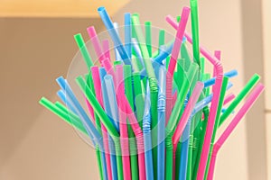 Top of several drinking straws made of plastic with different colors with blurred background.