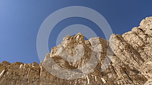 The top of a sheer cliff, devoid of vegetation, against the blue sky