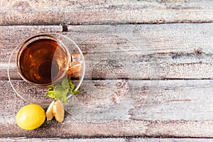 Top shot of black tea with mint leaves,lemon, ginger slices placed on wooden surface and copy space