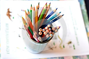 Top shot, close up of different, used, blunt, dull and sharpened colored pencils on bright papers background, space for text,