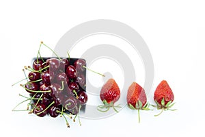 Top shot, close up of fresh sweet cherries with water drops in white bowl and strawberries isolated on white background, selective