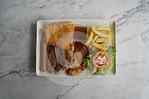 Top Shot of Meat Platter served with Fish Fillet, Sausage, Grilled Lamb, Grilled Pork, French Fries and Vegetables