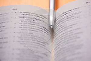Top shot of an open Christian Bible with the tip of a pen in the middle depicting Bible study and fellowship photo