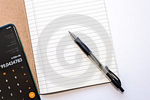 top shot of an opened lined notebook with a pen and a mobile phone