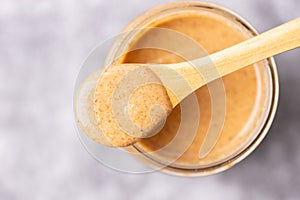Top shot of a wooden spoon and peanut butter in a glass cup