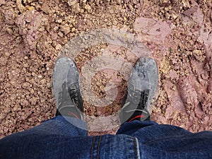 Top or side view of construction worker standing on construction site while wearing safety shoes. The shoes are dirty and dusty.