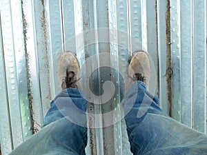 Top or side view of construction worker standing on construction site while wearing safety shoes. The shoes are dirty and dusty.