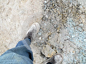 Top or side view of construction worker standing on construction site while wearing safety shoes. The shoes are dirty and dusty.