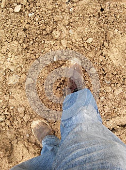 Top or side view of construction worker standing on construction site while wearing safety shoes. The shoes are dirty and dusty.