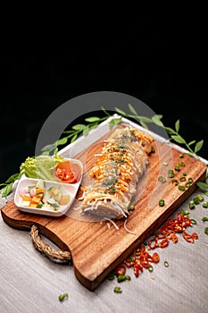 Top Side View Of A Fancy Eggroll With Herbs, Spices and Vegetables On A Chopping Board