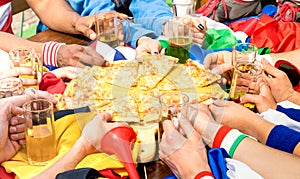 Top side view of multiracial hands of football friends supporter sharing pizza margherita at restaurant - Friendship concept