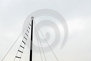 Top of small ship masts in sky cloud background copy space with rope ladder used to observe