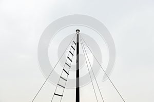 Top of small ship masts in sky cloud background copy space with rope ladder used to observe