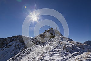 Top of snow-capped Seceda mountain in the Italian Dolomites in sunny weather with blue sky and clouds. The lens reflexes are also