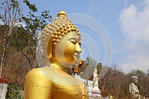 The top Thai temple has a large golden Buddha image. Natural background