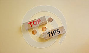 Top tips symbol. Concept words `top tips` on wooden blocks on a beautiful white background, metallic coins. Business and top tip