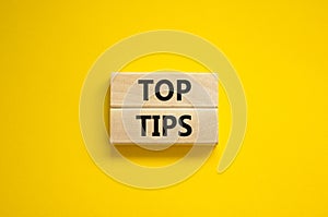Top tips symbol. Concept words Top tips on wooden blocks on a beautiful yellow background. Business and Top tips concept, copy