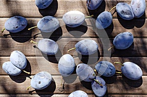 Top vie of juicy damsons plums on the wooden table as a background. Delicious sweet seasonal fruits