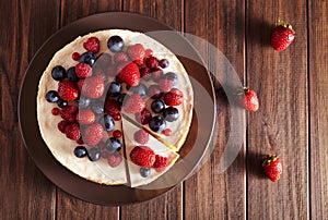 Top viev. Delicious Homemade creamy mascarpone New York Cheesecake with berries on dark wooden table. Close up.