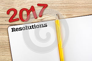 Top view of 2017 resolutions red number with blank open notebook
