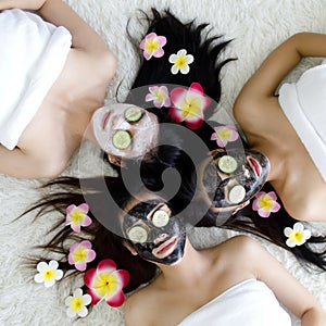 Top view for 3 Asian women sleep on white carpet in spa, her has long black hair, sliced cucumber close eye, face masked with