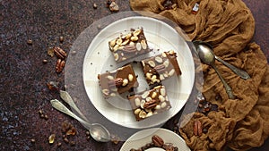 Top view of 4 square dark peanut brownies with nuts on a ceramic saucer