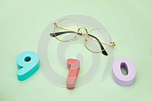 Top view of 910 numbers with eyeglasses on a light green surface