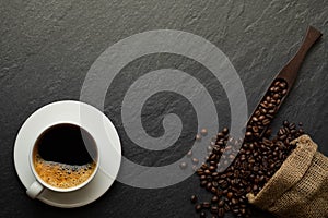 Top view above of Black hot coffee for morning with milk foam for morning menu in white ceramic cup with coffee beans roasted in s