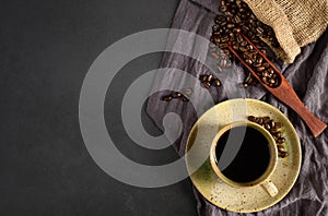 Top view above of Black hot fresh coffee in brown ceramic cup with coffee beans roasted