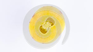 Top view from above of a cut in half mature yellow pepino. Rotating on the turntable isolated on the white background